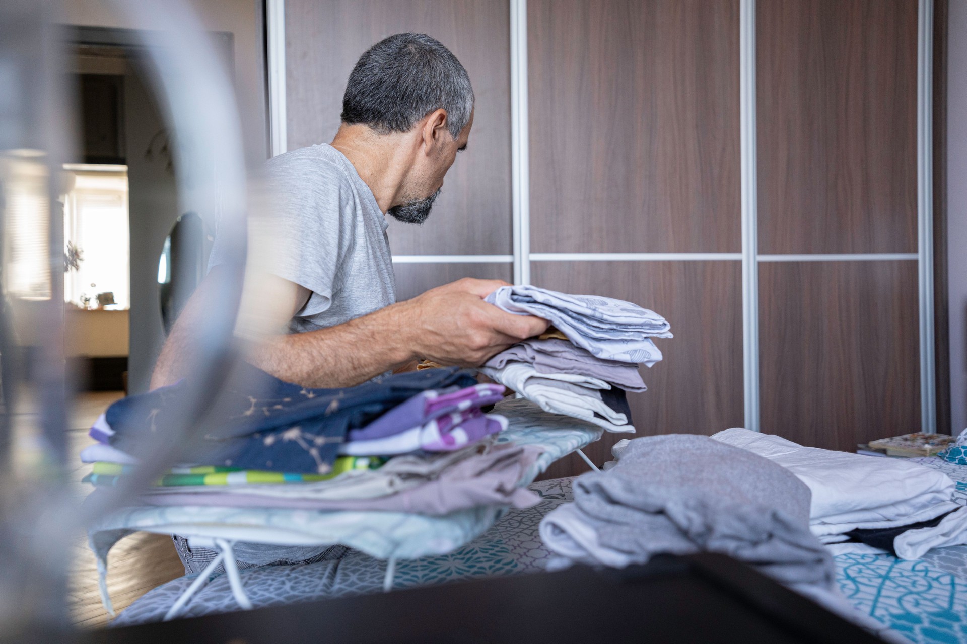 Mature Man Ironing Clothes, Doing Chores at Home.